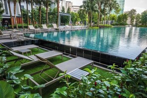 Une piscine avec des chaises longues et une pelouse.