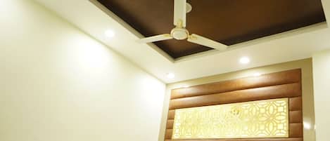 Un dormitorio moderno con cama, ventilador de techo, iluminación empotrada y un panel decorativo en la pared.