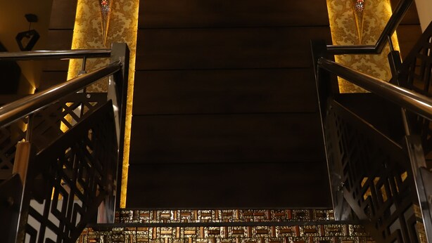 A modern interior with a patterned wall, a staircase, and a light fixture. - HOTEL SOLUXE (Jagadhri)