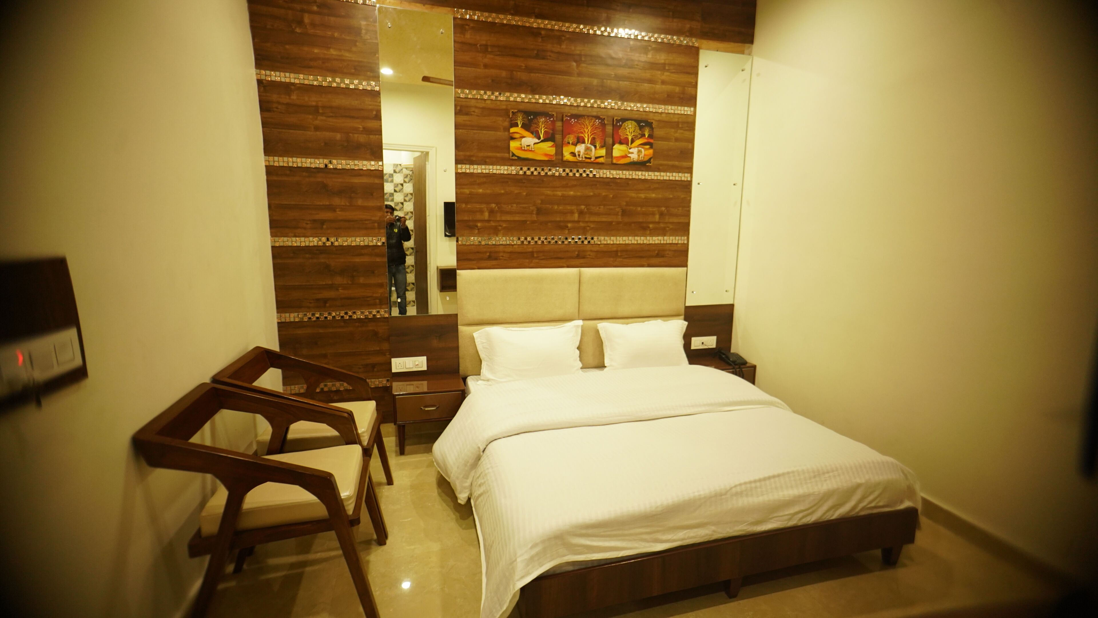 A hotel room with a bed, a wooden headboard, a nightstand, a chair, and a mirror.