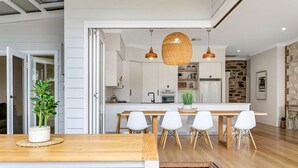 Una cocina moderna con armarios blancos, una isla central e iluminación colgante.