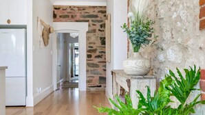 Un pasillo con pared de piedra, suelo de madera y una puerta blanca.