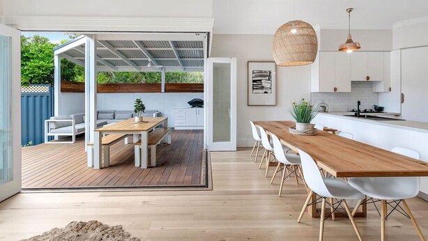 Una cocina moderna con armarios blancos y una mesa de comedor de madera.