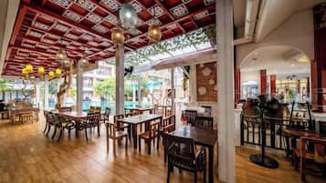 Un espacio interior para comer con suelo de madera, mesas, sillas y lámparas colgantes.