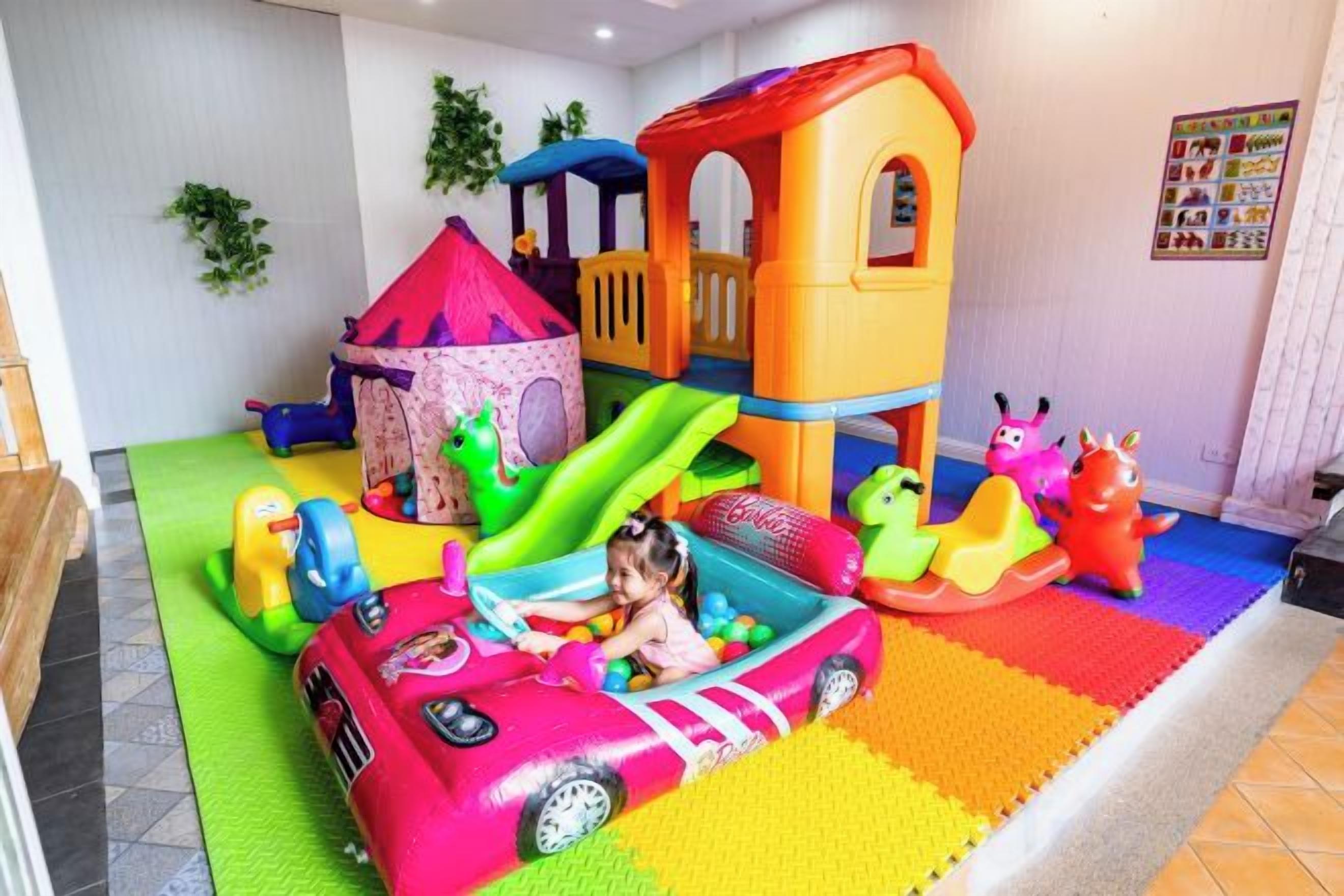 A children's play area with a slide, a playhouse, and a toy car.