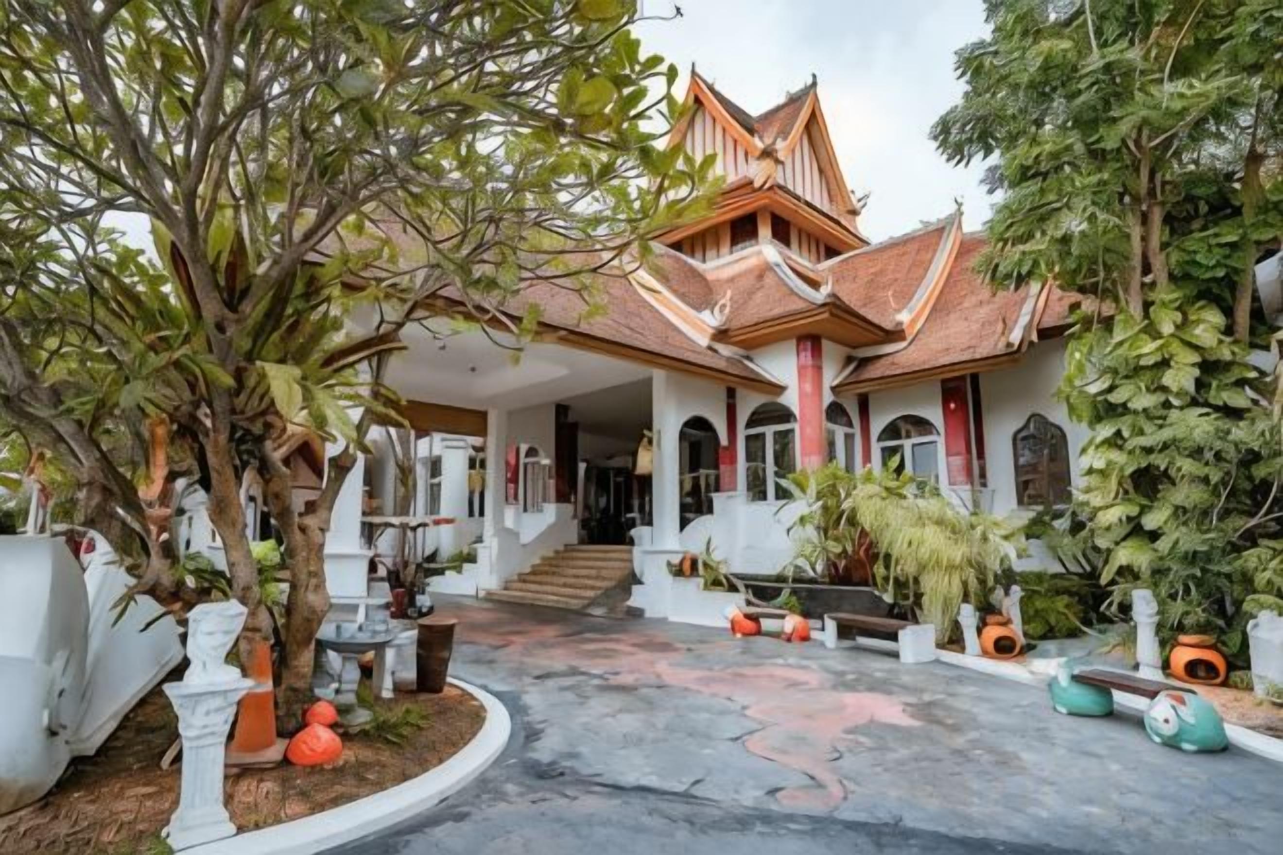 A traditional building with a tiled roof, a covered entrance, and a garden with potted plants and a tree.