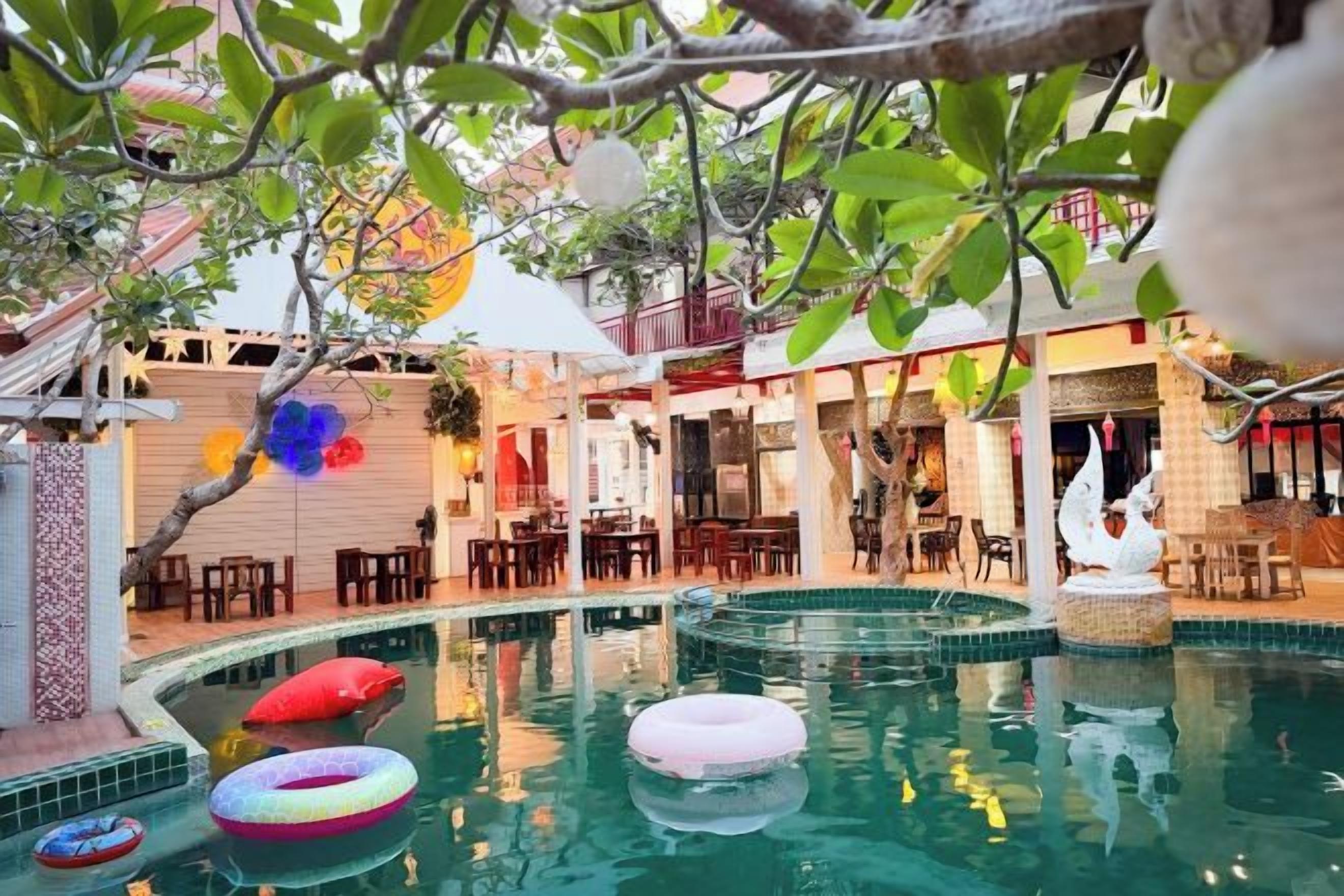 A pool area with multiple inflatable rings, a dining area with tables and chairs, and a decorative swan statue.