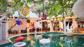 A pool area with multiple inflatable rings, a dining area with tables and chairs, and a decorative swan statue.