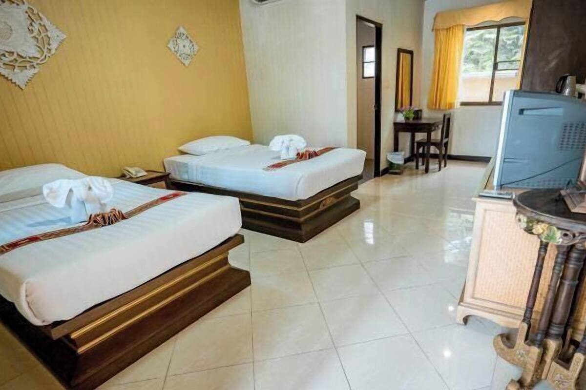 Une chambre d’hôtel avec deux lits, un bureau, une télévision et une armoire.