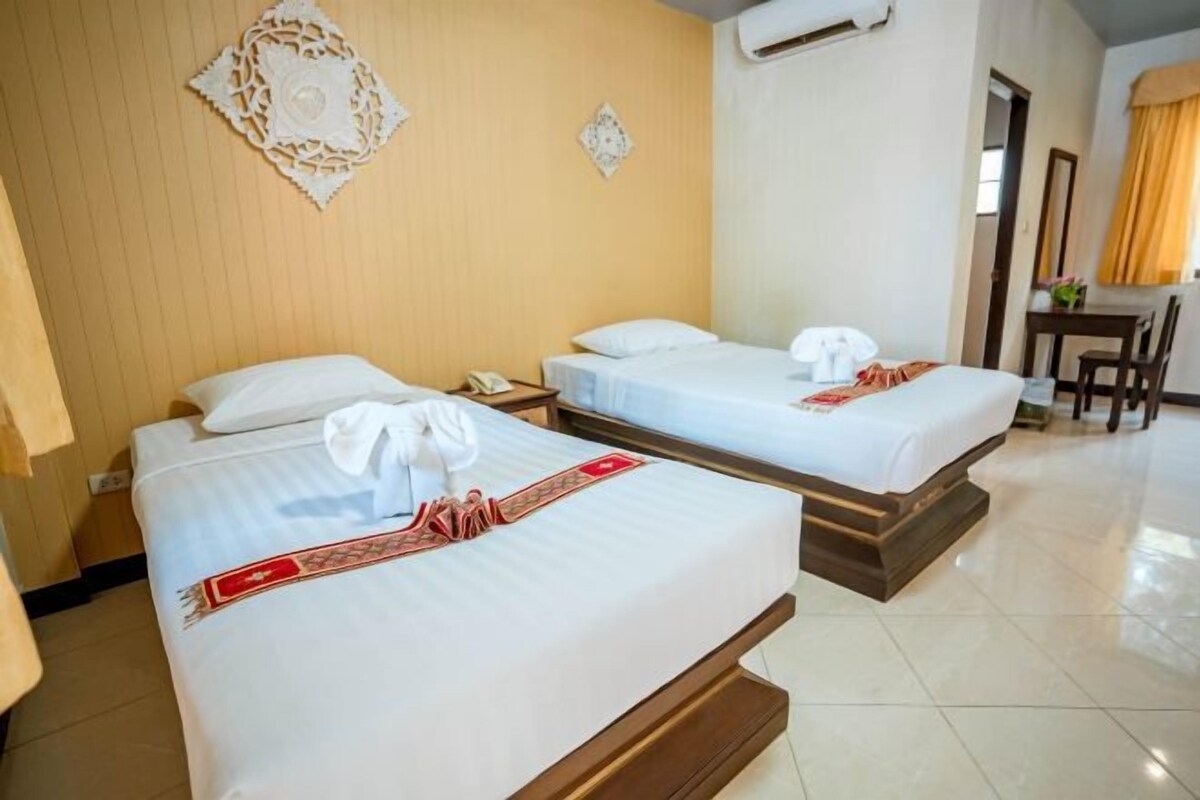 A hotel room with two beds, a desk, and a chair.