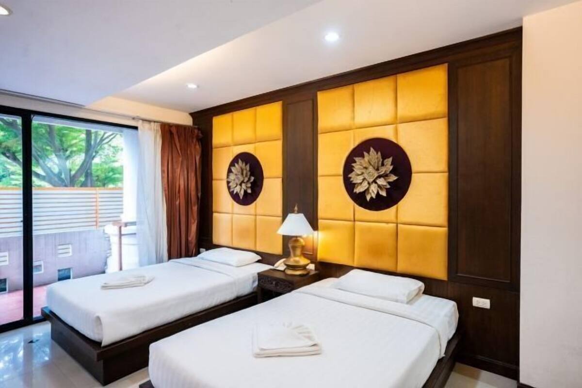 Une chambre d’hôtel avec deux lits, une grande fenêtre et une vue sur la verdure environnante.