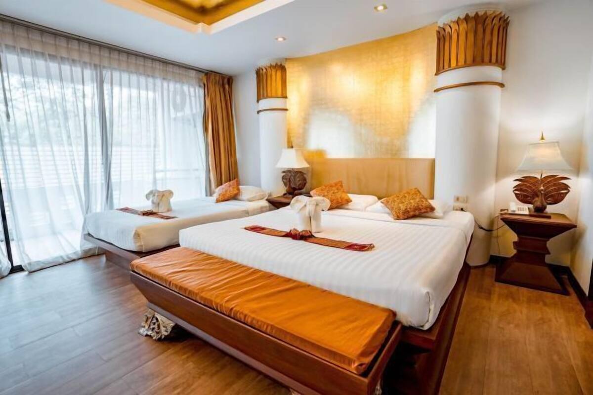 Une chambre d’hôtel avec deux lits, une grande fenêtre avec des rideaux, un plancher en bois et un panneau décoratif au mur.