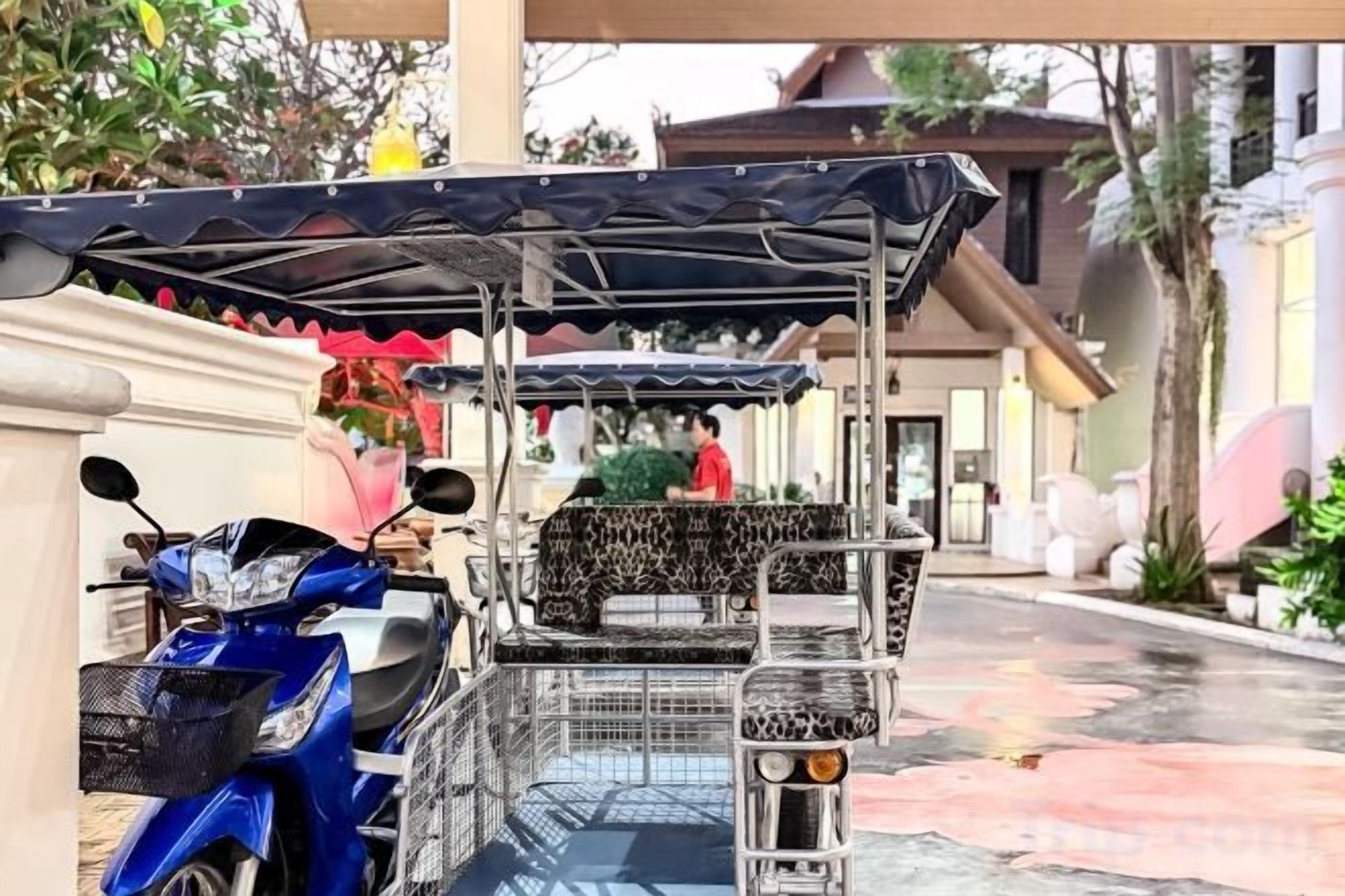 A covered parking area with a blue scooter and a covered cart.
