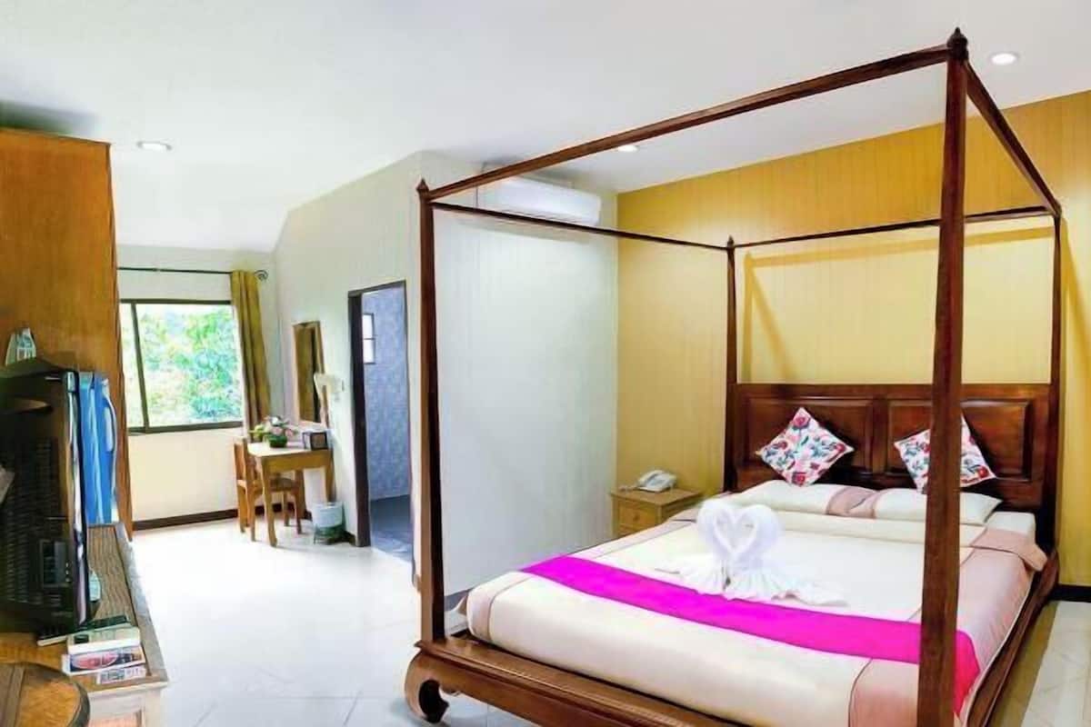 Un lit à baldaquin avec un cadre en bois, une table de chevet avec une lampe et une fenêtre avec des rideaux.