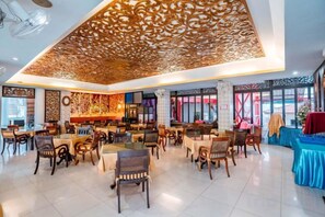 A spacious restaurant with multiple dining tables and chairs, a decorative ceiling, and large windows. - Lanna Hotel by Kasalong Resort and Spa Pattaya (Pattaya)
