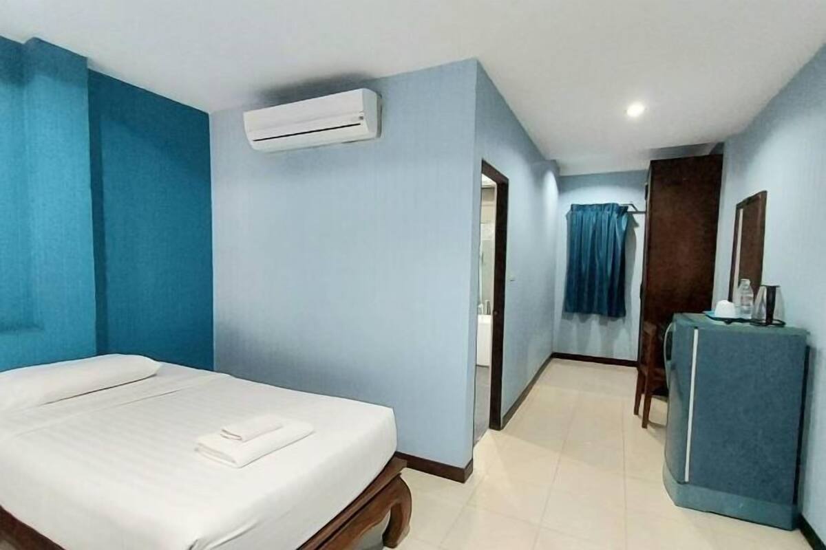 Une chambre d’hôtel comprenant un lit, un appareil de climatisation, un bureau avec une chaise et un miroir.