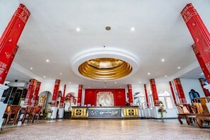 Hotellin aula, jossa on vastaanottotiski, oleskelualue ja suuri koristeellinen seinä.