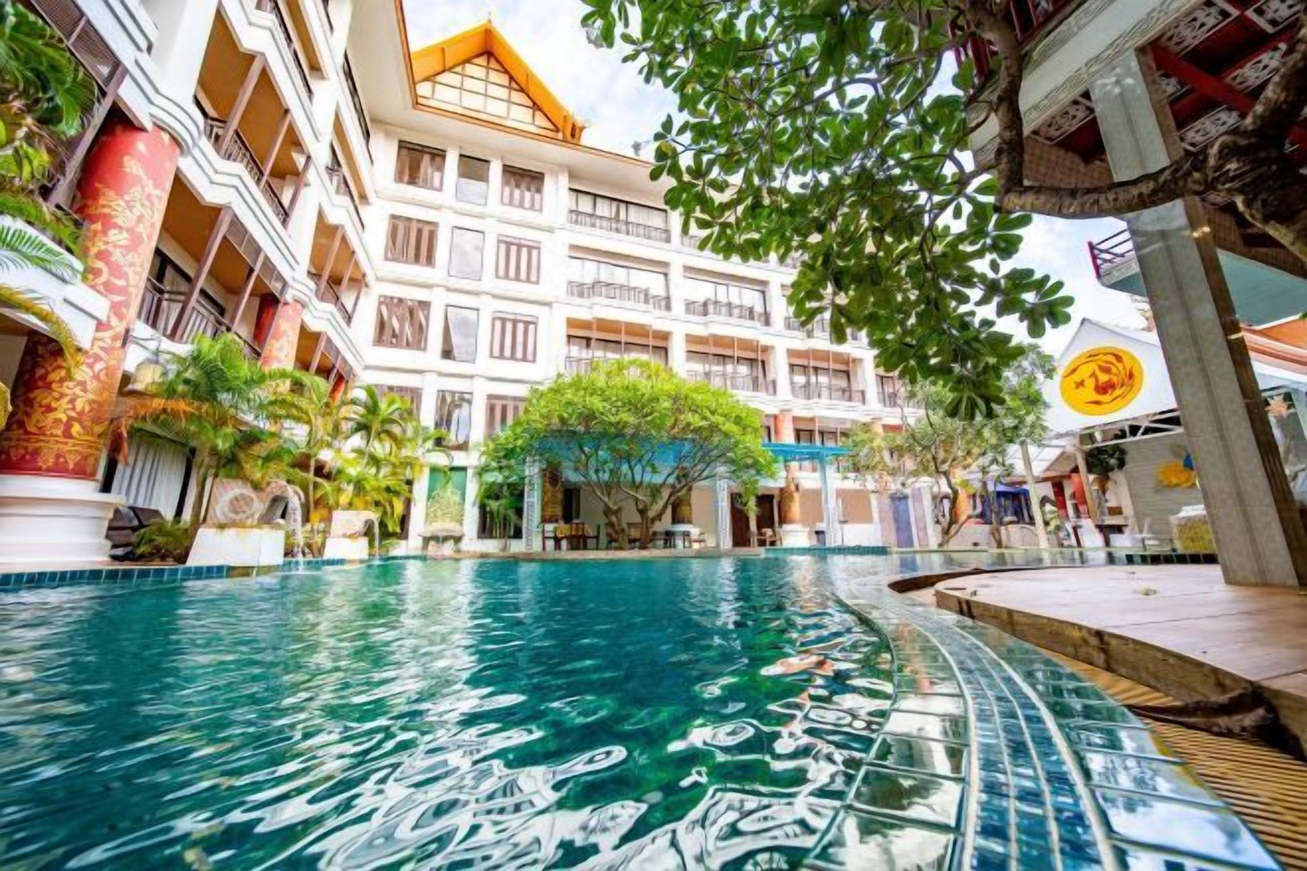 Un hotel con piscina, varios balcones y un área exterior cubierta.