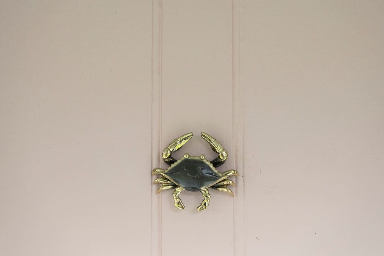 Un seul objet métallique en forme de crabe, posé sur une surface plane.