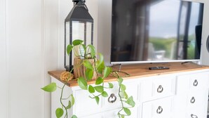 A TV on a wooden cabinet with a plant and a lantern.