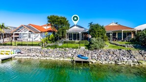 A waterfront property with a stone dock, a gazebo, and a house with a red roof.