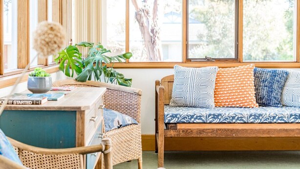 Une pièce chaleureuse avec un banc en bois, une petite table sur laquelle est posé un pot de plantes et une bibliothèque.