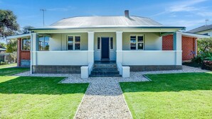 Une maison moderne à deux étages, dotée d’un toit plat, d’un porche à l’avant et d’une pelouse bien entretenue.