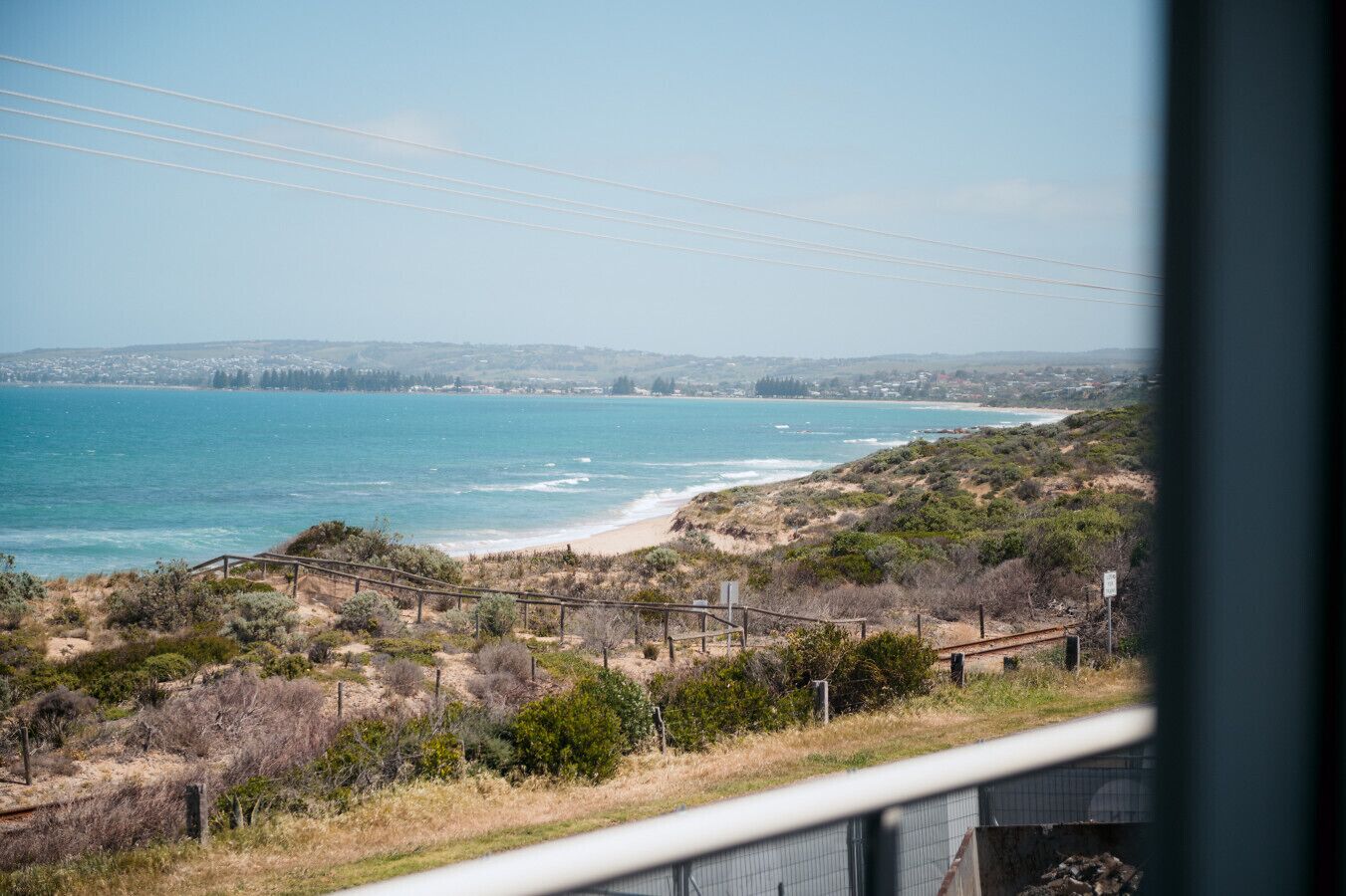 A coastal landscape with a beach, vegetation, and a distant cityscape.