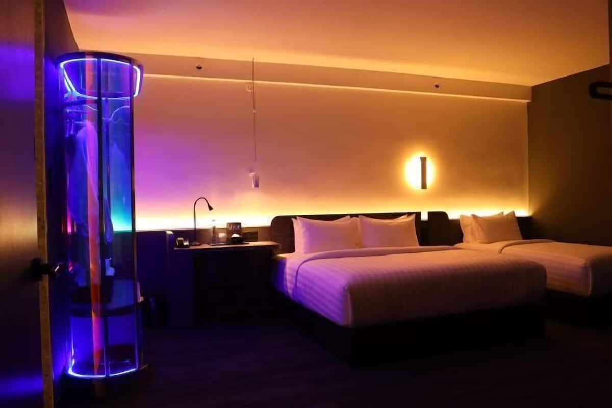 Camera d'albergo con un letto, comodino e una lampada a parete.
