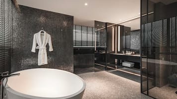 Une salle de bain moderne avec une grande baignoire, un porte-peignoir suspendu et une douche séparée par une paroi de verre.