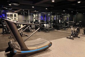 Een sportschool met trainingsapparatuur, waaronder een loopband en gewichtstoestellen.