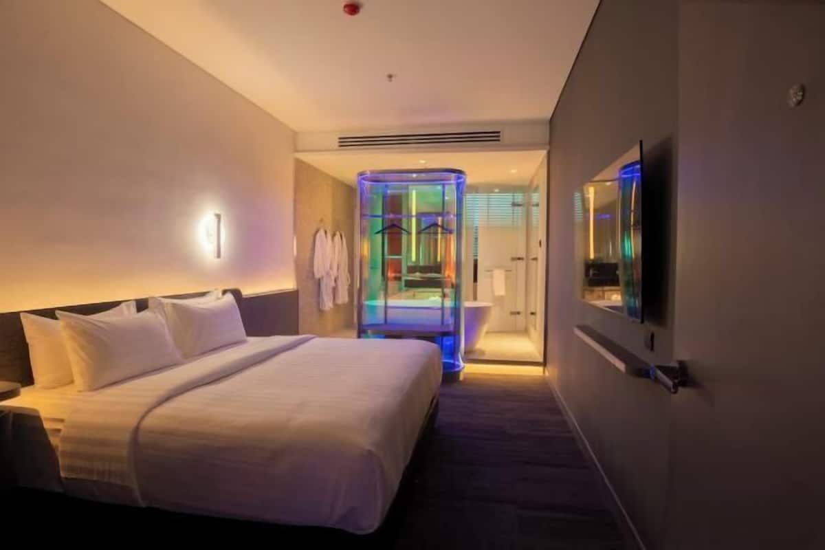 Una camera d'albergo con un letto, una TV, un bagno con cabina doccia in vetro e una doccia.