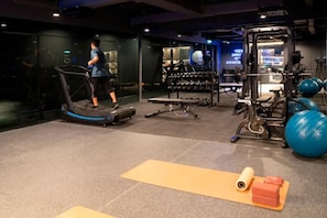 Egy edzőterem futópaddal, súlyzókkal és fitneszlabdákkal felszerelve.