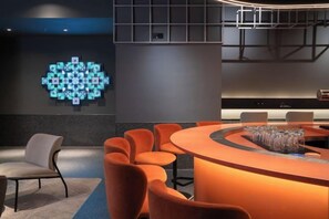 A modern conference room with a curved table, orange chairs, and a unique wall art installation. - CapsuleTransit MAX - Terminal 2 (Sepang)