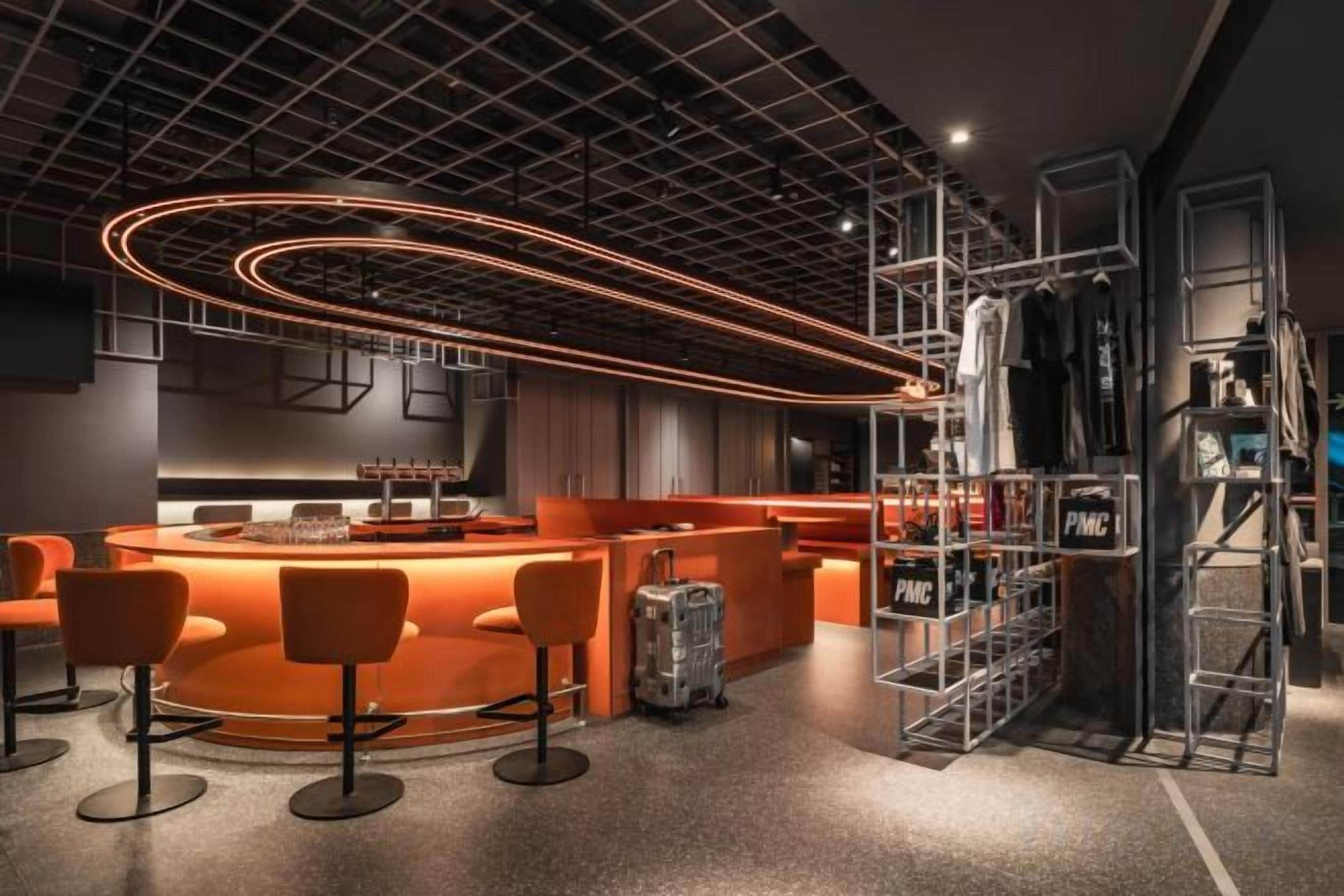Eine moderne Bar mit einer gebogenen Theke, Barhocker und einem Metallregal mit Flaschen.