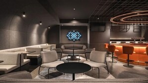 A modern lounge area with a central round table, sofas, and a bar counter. - CapsuleTransit MAX - Terminal 2 (Sepang)