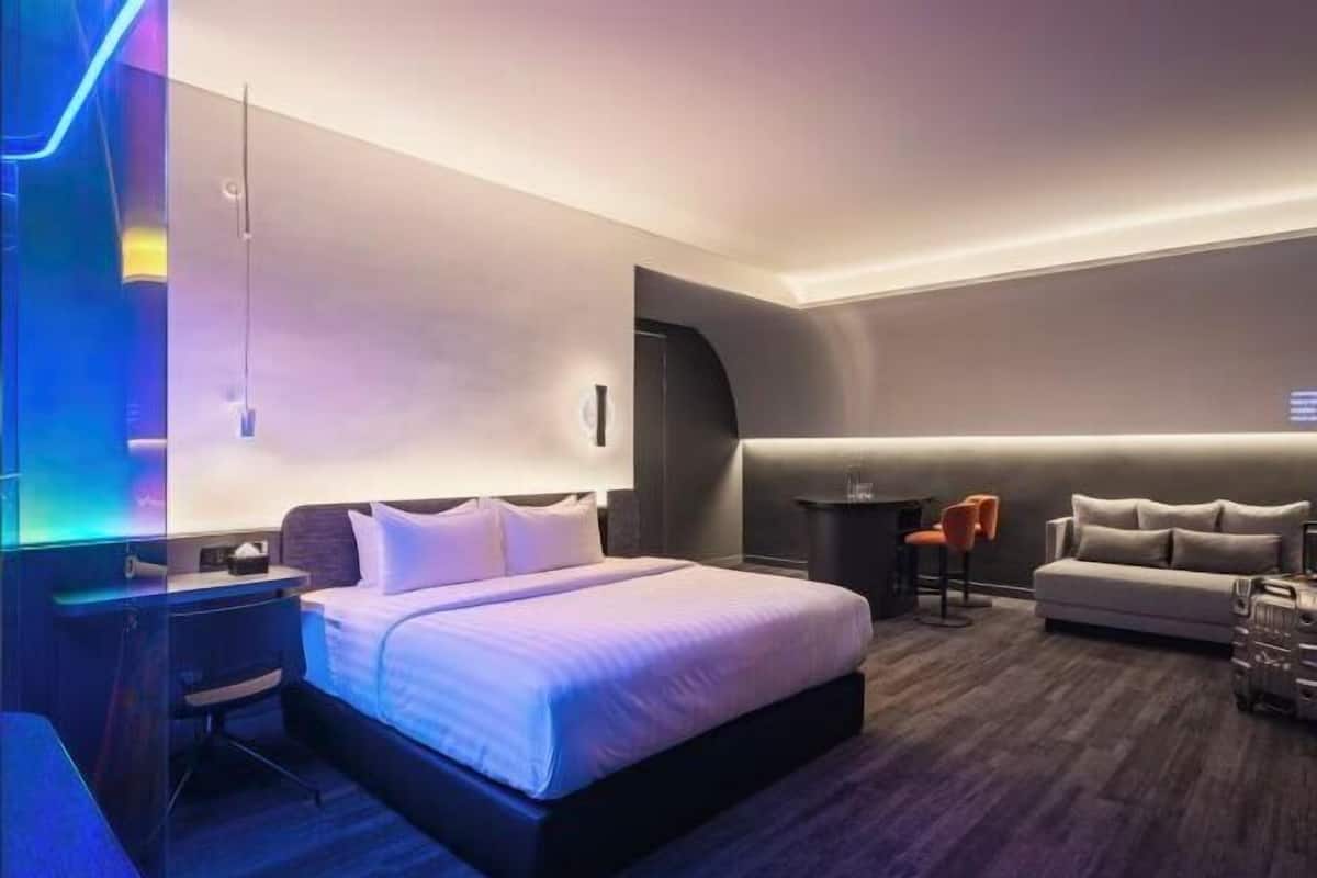Una camera d'albergo moderna con un letto, una scrivania, un divano e un tavolino.
