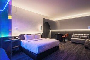 Una habitación de hotel moderna con una cama, un escritorio, un sofá y una mesita.