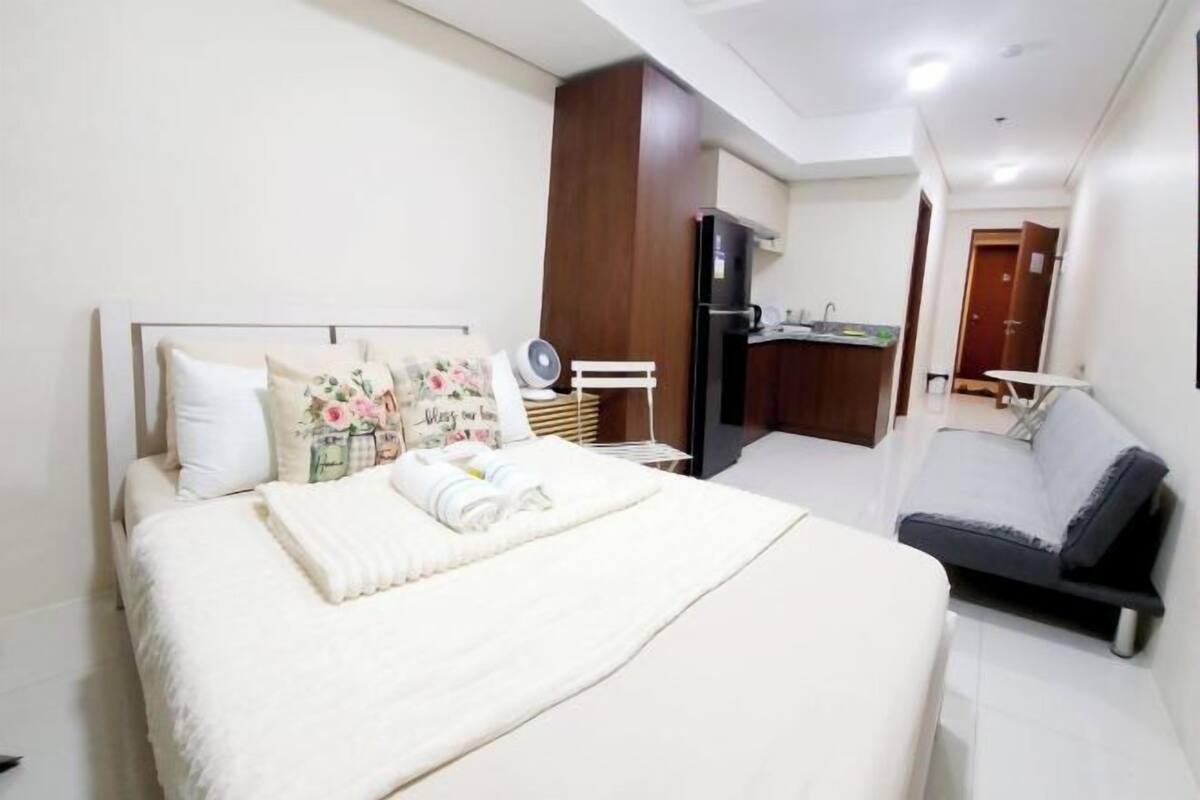 Ein Hotelzimmer mit einem Bett, einem Schlafsofa, einem Schreibtisch, einem Spiegel, einem Kleiderschrank und einer Tür.