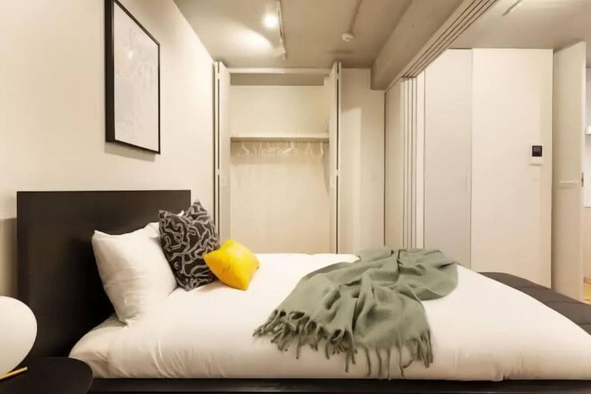 A modern bedroom with a large bed, a bedside table, and a wardrobe.