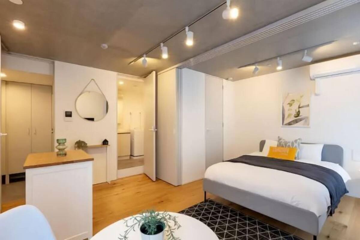 A modern bedroom with a bed, bedside table, and a small potted plant.