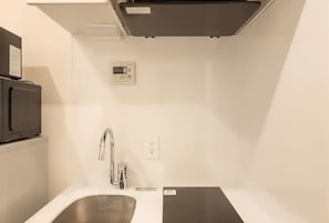A compact kitchen with a stainless steel sink, a microwave, and a built-in oven.