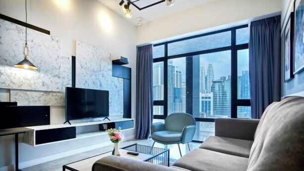 Una sala de estar moderna con un ventanal grande, un televisor de pantalla plana, un sofá, una silla y una mesa de centro.