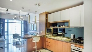 Una cocina moderna con una isla central, electrodomésticos integrados y una zona de comedor con un taburete de bar.