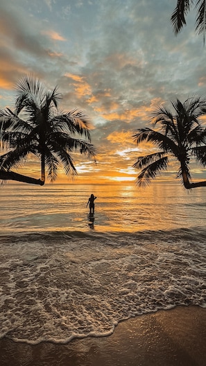 A beach scene with palm trees and a sunset.