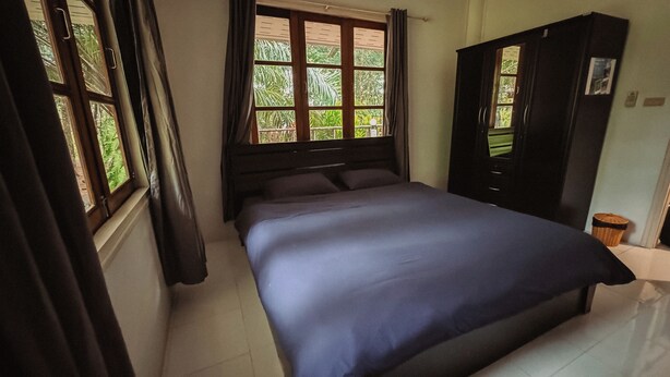 Un dormitorio con cama, armario y ventana con cortinas.