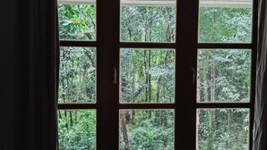 Quarto com cama, janela com cortinas e ar condicionado sobre a janela.