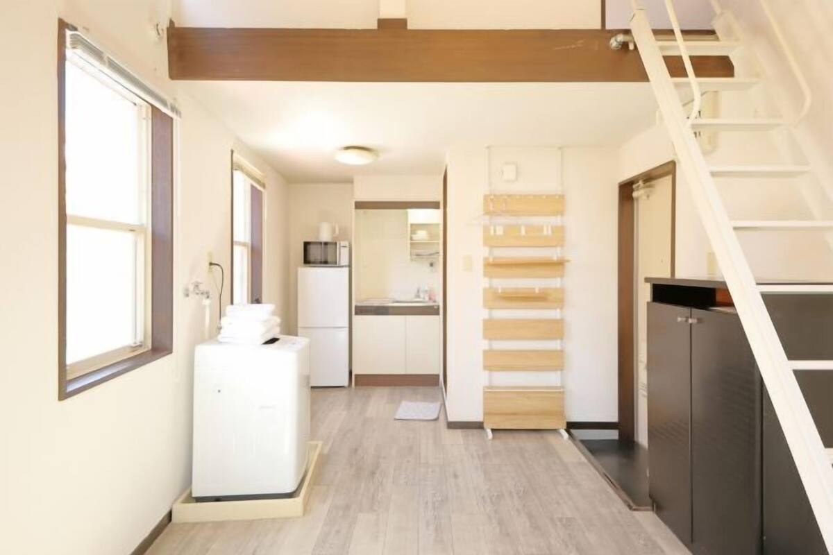 A narrow hallway with a kitchen area, a staircase, and a laundry room.