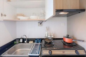 Een kleine keuken met een fornuis, spoelbak en een afwasschuurrek.
