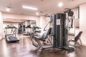 Een sportschool met cardioapparatuur, gewichten en een spiegelwand.